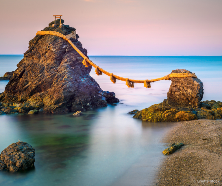 een kalme zee met een paarse lucht op de achtergrond. Op de voorgrond staan twee rotsen, op de grotere rots aan de linkerkant staat een kleine shinto tempel. De rots is met een touw met decoratieve kwasten verbonden aan de kleine rots aan de rechterkant.