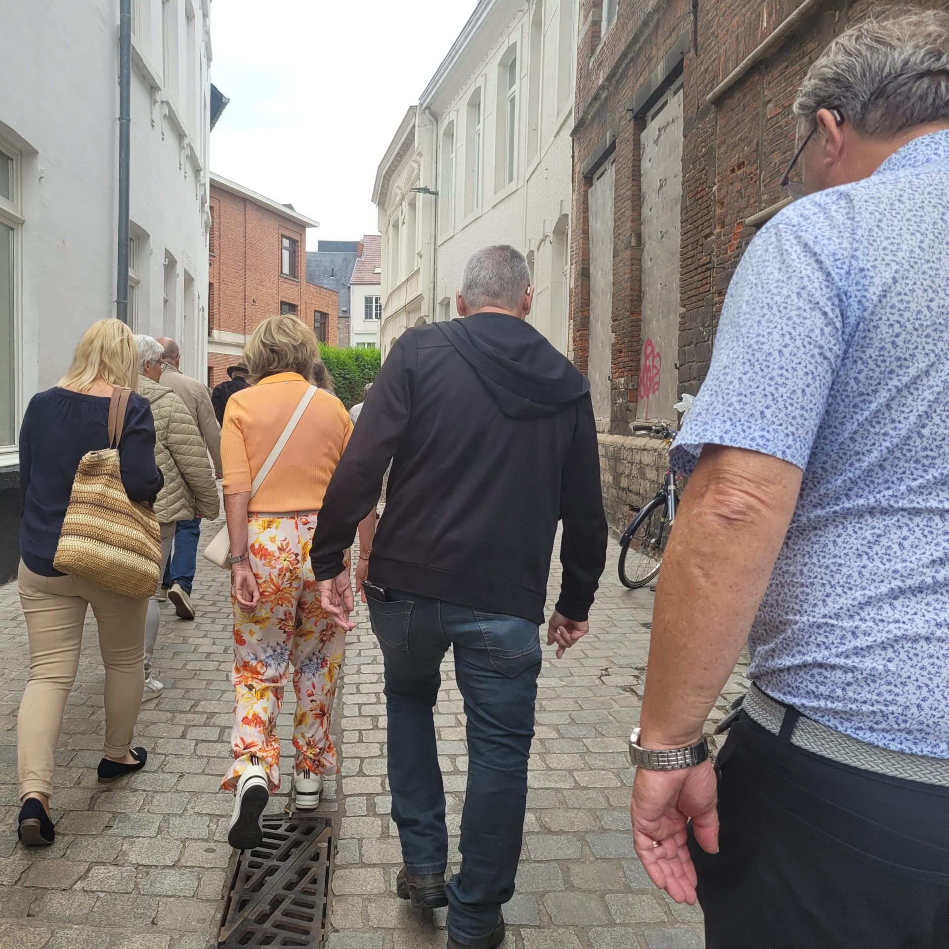 een groep mensen wandelt over straat, met de rug naar de camera