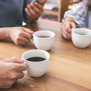 Closeup,Image,Of,People,Using,Mobile,Phone,And,Drinking,Coffee