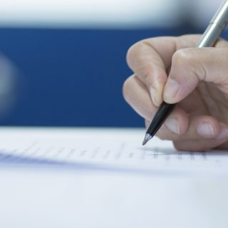 University,Students,Hand,Writing,Doing,Examination,With,Blurred,Abstract,Background